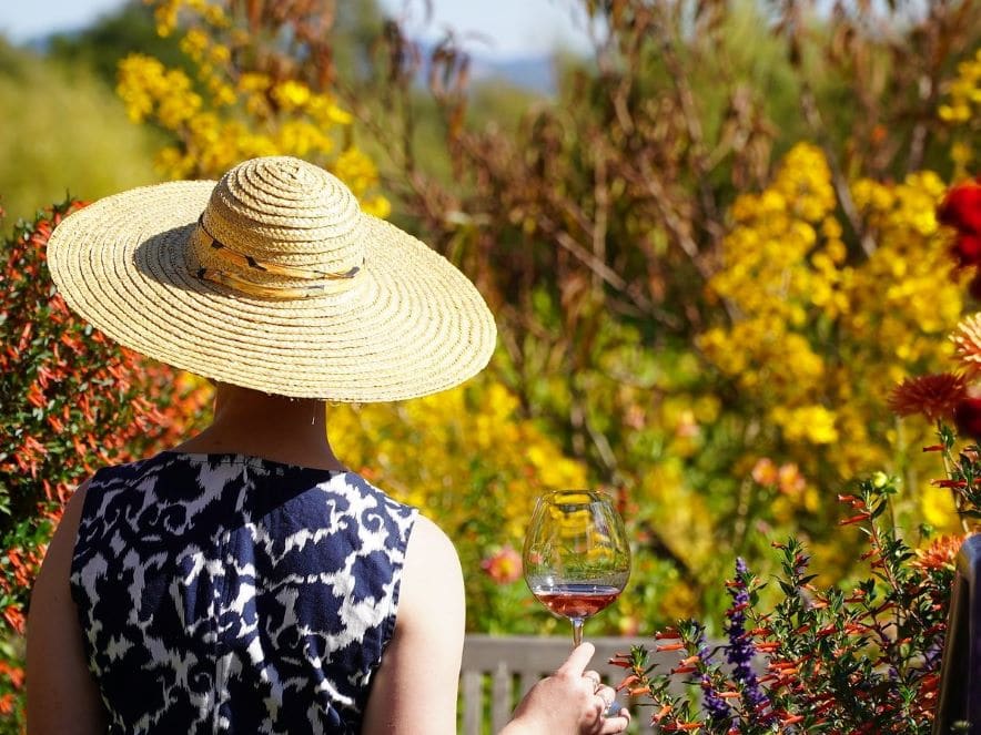 Picture of woman holding glass of wine amongst flowers