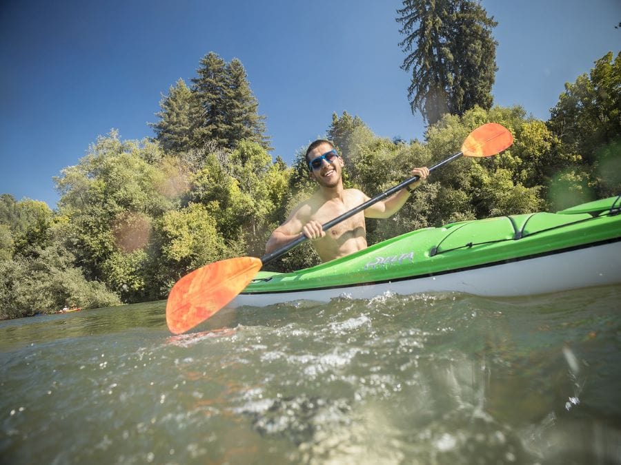 A person smiles while kayaking in the river