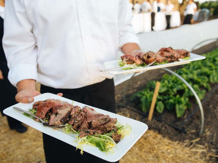 server holding meat and lettuce on long white plate