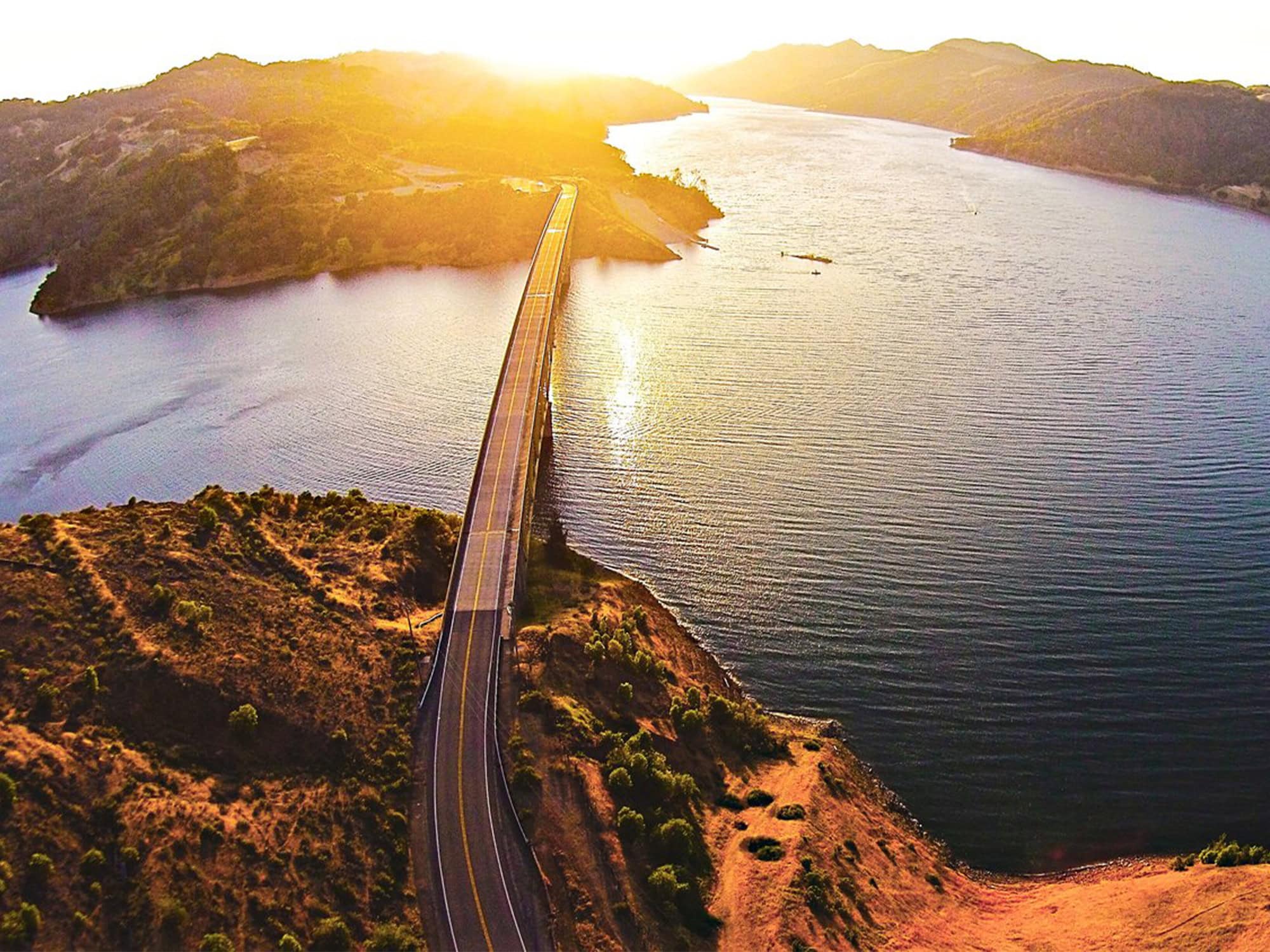 An aerial view of the bridge going across the lake at sunset