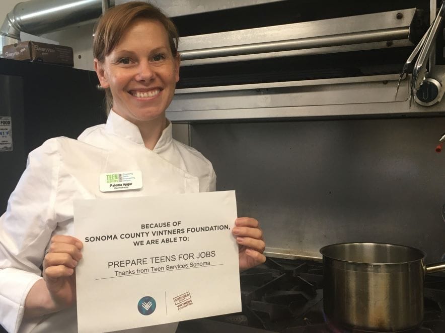 Picture of a woman holding up a sign in a kitchen