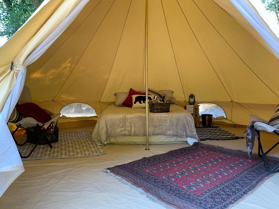 The interior of a fully-furnished glamping ten has rugs, lamps, and pillows in Sonoma County