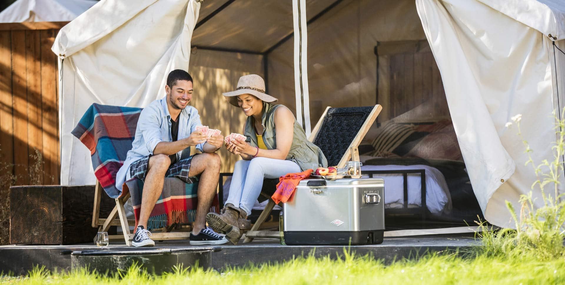 Couple playing cards outside tent at AutoCamp Russian River in Guerneville, CA.