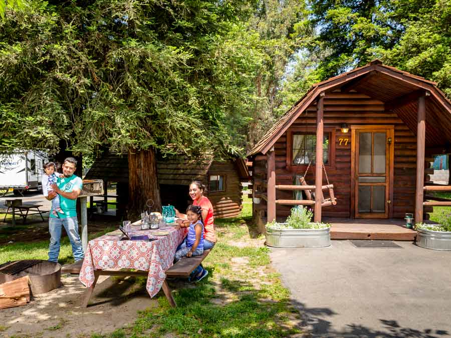 A family sits out front of a cabin at the KOA in Sonoma County