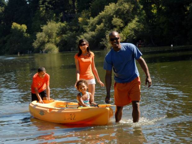 picture of family walking with kayak in a river