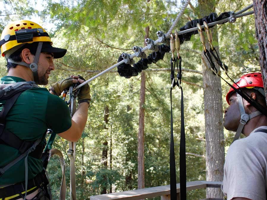 Two people are ready to zipline through trees