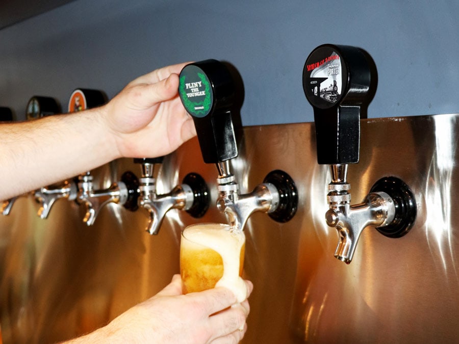 A person pours a glass of beer out of a tap