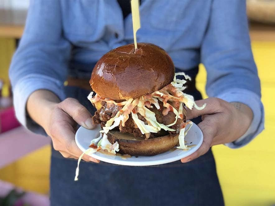 woman holding plate of fried chicken sandwich