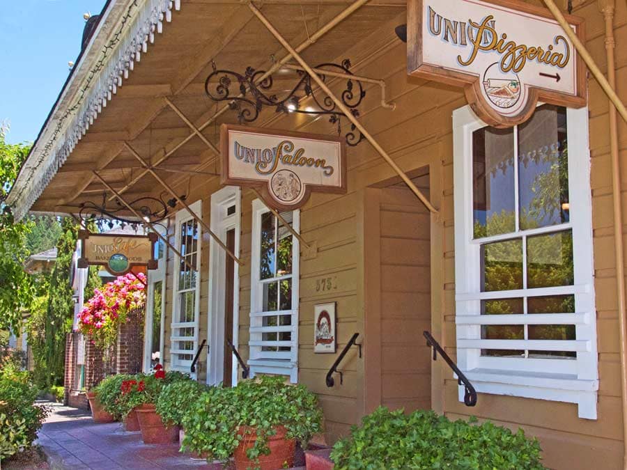 There are signs for restaurants under the awning of the building