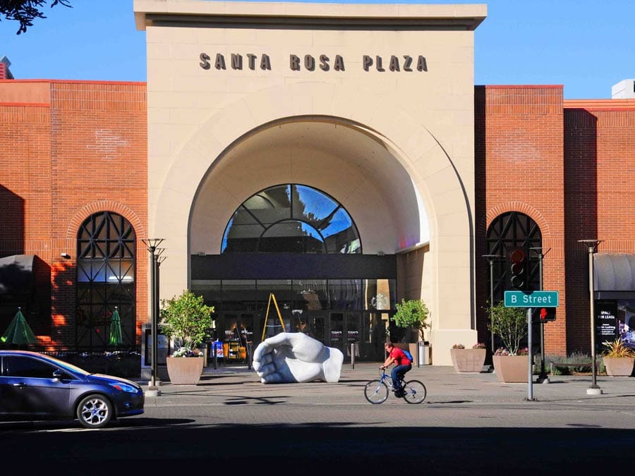 A sculpture of a curved hand sits outside of the mall