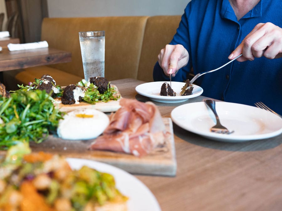 A person eats at a table with burratta and a salad at Catelli's in Sonoma County