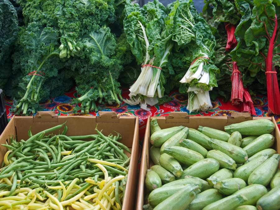 Chard, zucchini, and green beans on display on a table at the farmers market