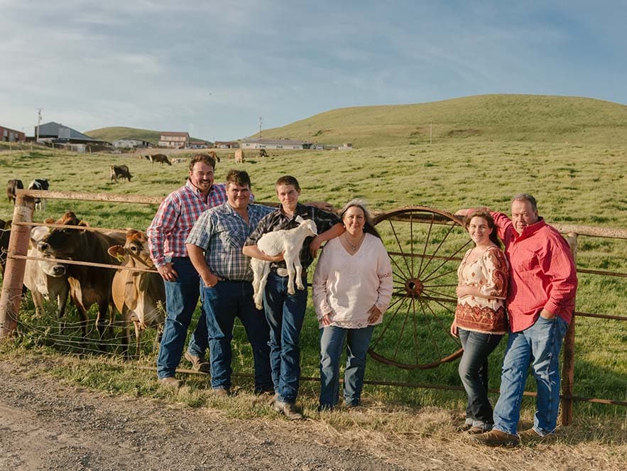 portrait of family with dogs in field with cows and green hills