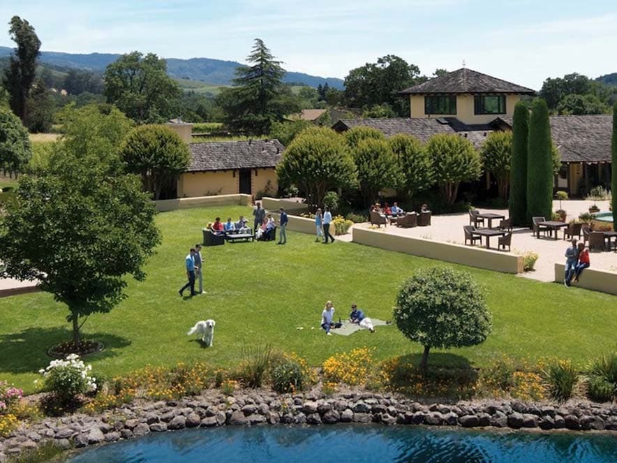 people on lawn by pond and landmark vineyards building