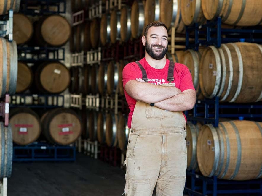 man standing in area with wine barrels