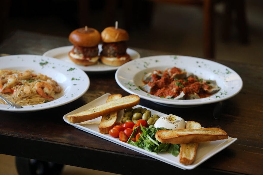 (Clockwise from bottom) Burrata Di Stefano appetizer platter, red chili prawn pasta, meatball sliders, and Nonna's homemade ravioli at Negri's in Occidental—Photo by Beth Schlanker