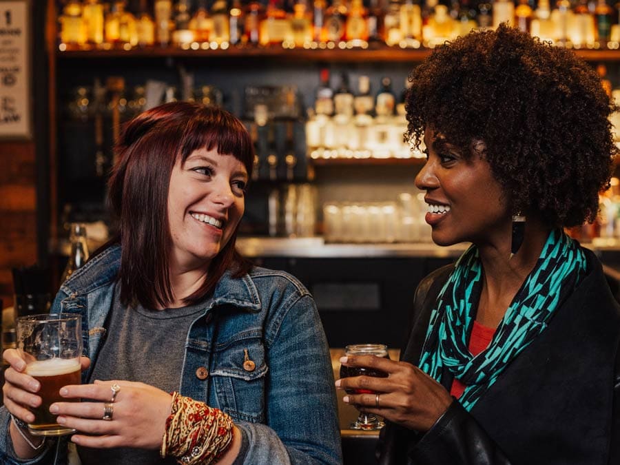 Two friends smile and enjoy beer at the bar