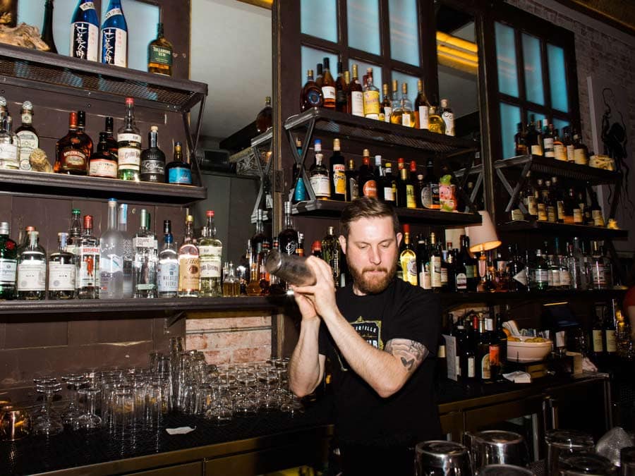 A bartender shakes at cocktail in front of a wall of booze in Sonoma County