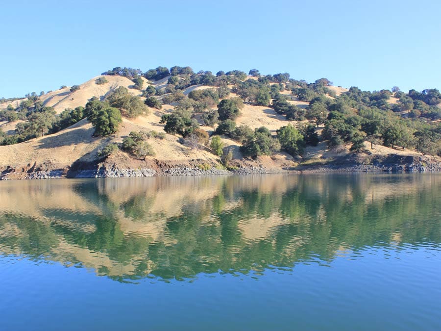 The mountains next to Lake Sonoma are reflected in the blue water