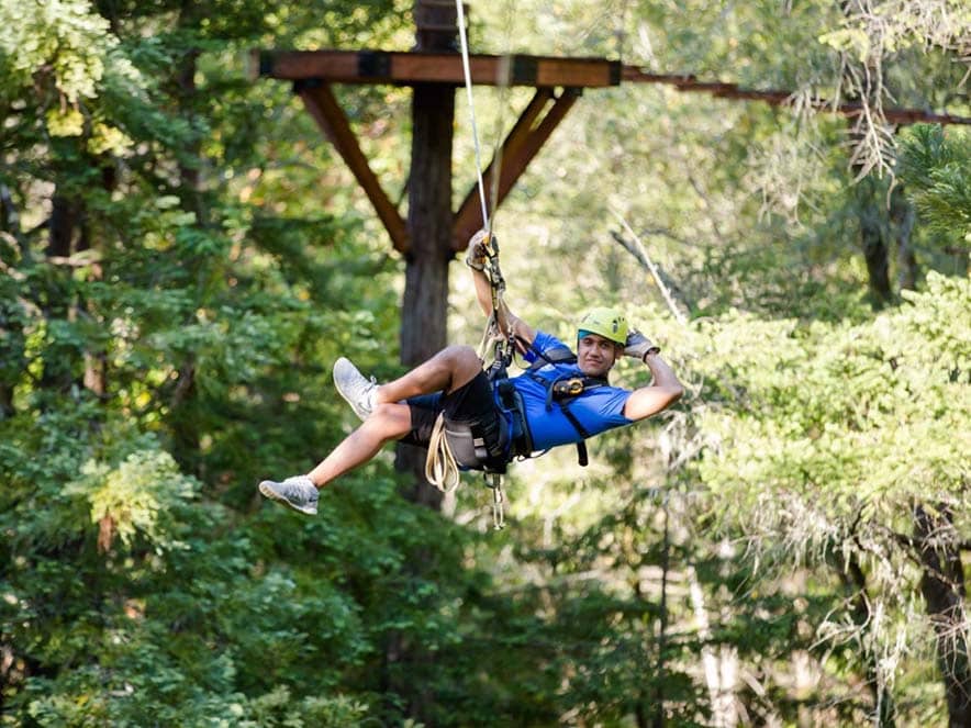 man posing on zipline among trees