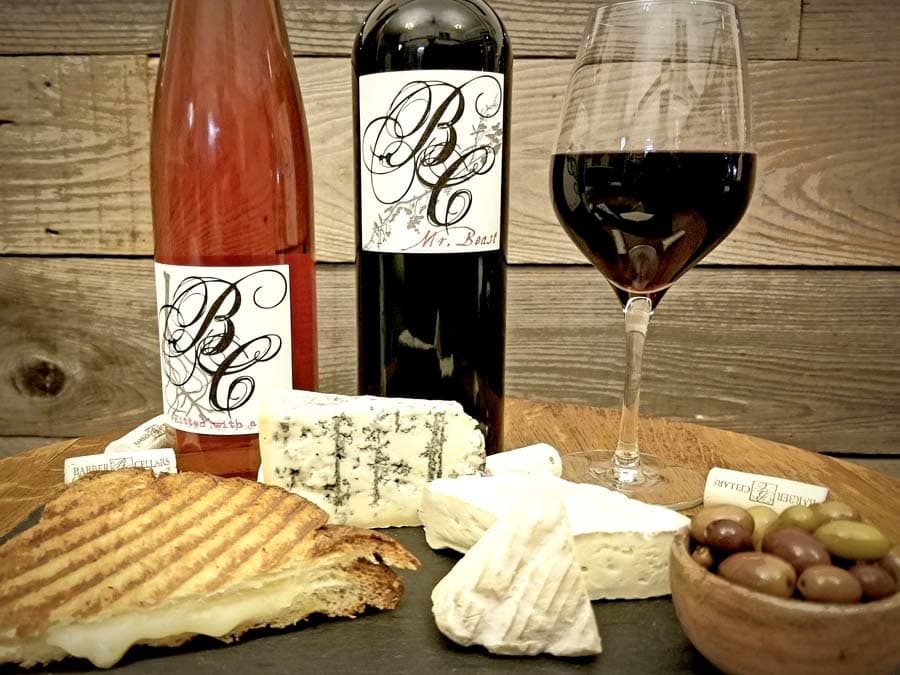 A bottle and a glass of wine next to cheese ready for a pairing