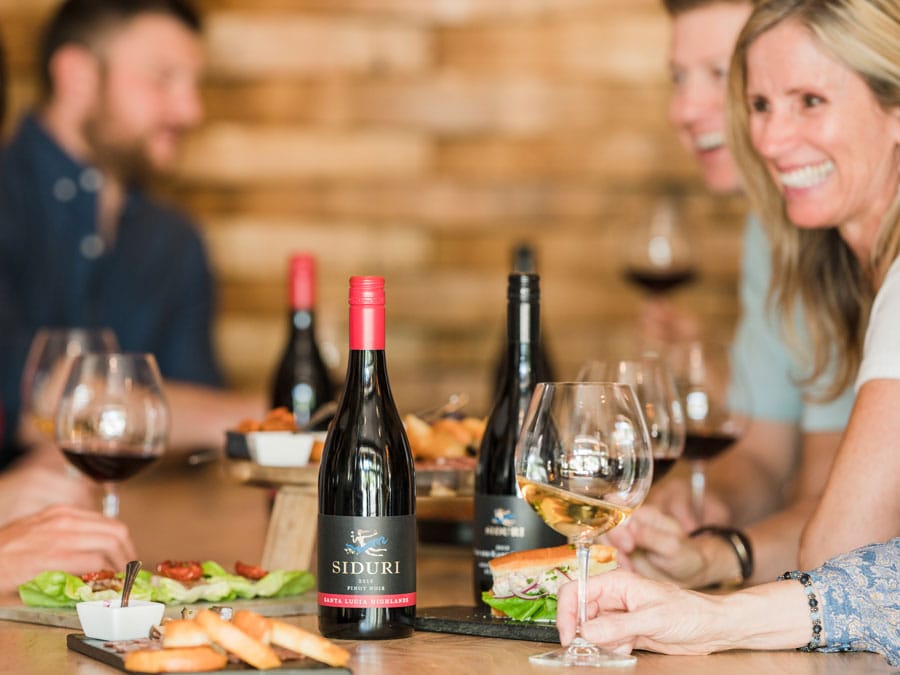 People enjoy wines at a table with snacks