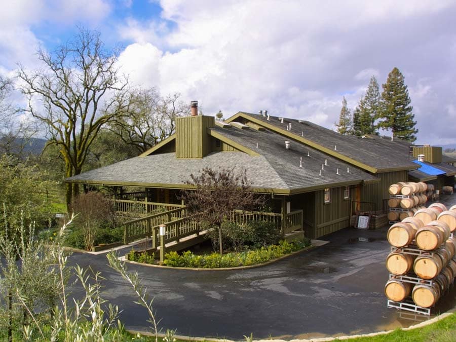 The winery looks wet after a rain and has barrels sitting outside