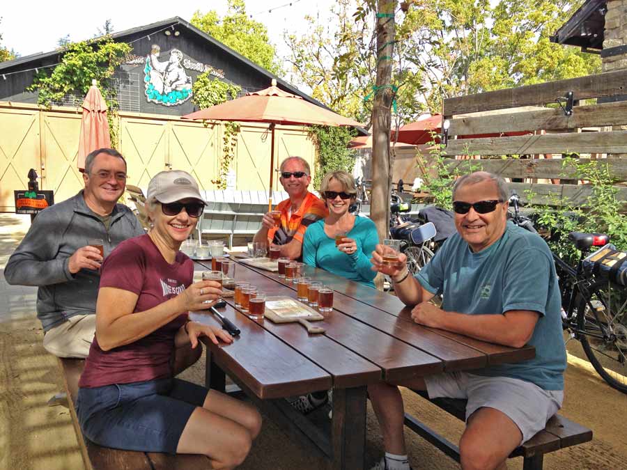 People sit at a picnic table drinking beer on a patio