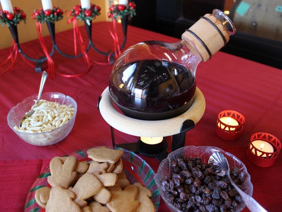 A jug of spiced wine, cookies, and raisons on a festive table