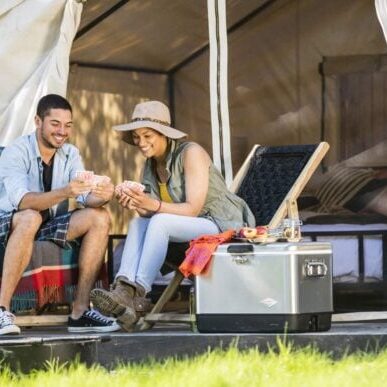 Couple playing cards outside tent at AutoCamp Russian River in Guerneville, CA.